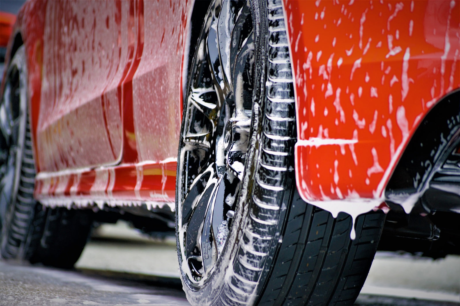 Car wash spray nozzles, shampoo on red car